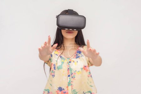 Photo for Portrait of playful woman with long brunette hair with vr headset playing game standing with outstretched hands. Indoor studio shot isolated on pink background. - Royalty Free Image
