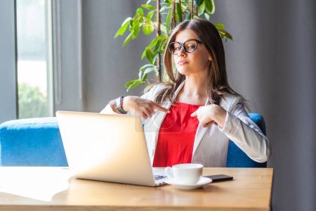 Photo for Portrait of proud confident woman working on laptop sitting at table pointing at herself with satisfaction, wearing jacket and re shirt. Indoor shot, cafe or office background. - Royalty Free Image