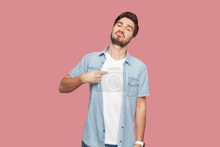 Photo for This is me. Satisfied proud bearded man in blue shirt standing points at himself, stands self confident, feels successful of his own achievement. Indoor studio shot isolated on pink background. - Royalty Free Image