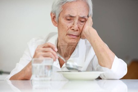Foto de Sick asian senior woman suffering from anorexia,bored with meal,eating less food,discomfort in swallowing,disease of Dysphagia,Old elderly patient with Anorexia-Cachexia syndrome,lack of appetite - Imagen libre de derechos