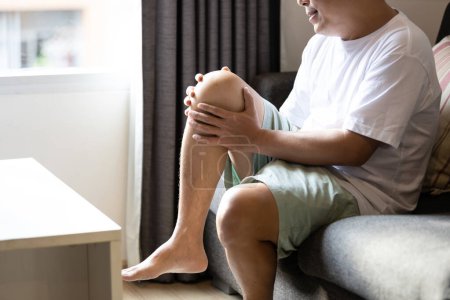 Téléchargez les photos : Homme d'âge moyen asiatique souffrent d'arthrite, tendinite patellaire, symptôme de la goutte, dépôt de calcaires, inflammation douloureuse et raideur des articulations, blessures ligamentaires, sensation de picotements dans le genou - en image libre de droit