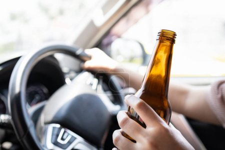 Téléchargez les photos : Femme en état d'ébriété conducteur tenant une bouteille de bière, femme asiatique buvant de l'alcool au volant, risque ou danger d'accident de la route, Campagne contre la conduite en état d'ébriété, concept de "ne pas boire et conduire" - en image libre de droit