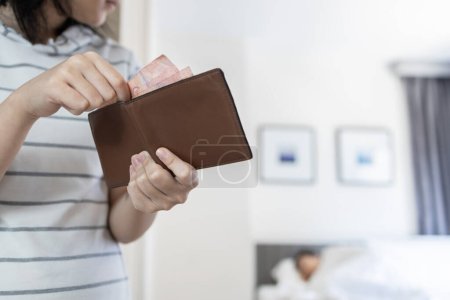 Photo for Teenager girl trying to steal money carefully pulling cash out of wallet skillfully,moving quietly in her parent's bedroom at home,bad habit,behavior of stealing for hangout,shopping,lifestyle concept - Royalty Free Image