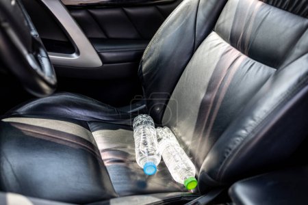 Plastikflasche Wasser auf Autositz gelegt und Sonne an sonnigen Tagen ausgesetzt, Flasche Trinkwasser im Auto, Sonnenlicht, sehr heiß, Heiztemperatur, verursachen Gefahr, wenn sie lange in der Sonne geparkt wird