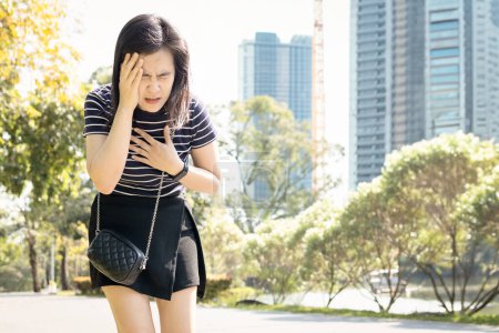 Tired asian woman with dizziness,Heat stroke,walking outdoor on sunny day,hot weather,high temperature in summer,sweaty and thirsty,Arrhythmia symptoms,heart beats with an irregular or abnormal rhythm