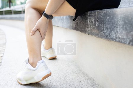 Photo for Asian woman have severe cramp her calf of leg,muscle strain,female massaging leg with her hands,suffering from muscular spasms and cramps,contraction of muscles or tendons,physical injury,health care - Royalty Free Image