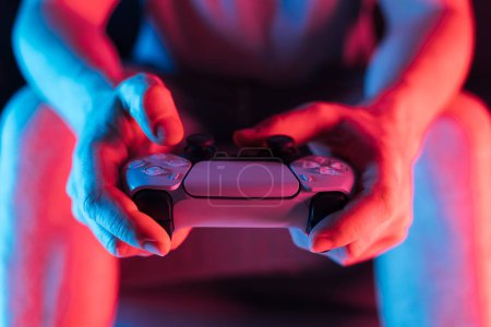 Man hands with game controller in neon light, front view. High quality photo
