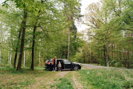 Téléchargez les photos : Mère avec enfant avec voiture dans la forêt. famille Voyage local en voiture. Photo de haute qualité - en image libre de droit