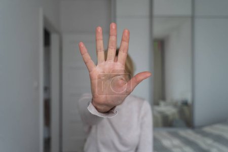 Photo for Woman showing stop gesture with hand at home. Abuse, mental health, toxic relationship problem. High quality photo - Royalty Free Image