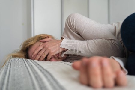 Femme mûre courbé couché sur le lit à la maison vue de dessus. Dépression, santé mentale, problèmes d'abus. Photo de haute qualité