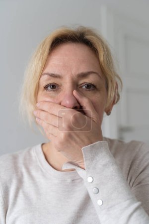 Téléchargez les photos : Triste femme mûre ferme la bouche avec la main. . Photo de haute qualité - en image libre de droit