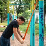 Middle age man doing strength exercises with resistance bands outdoors in park . High quality photo