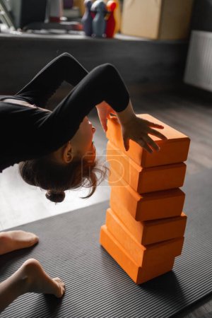 Photo for Preschool age child girl doing stretching exercises in dancing or yoga studio. Yoga blocks and sport mat. Back stretching flexibility. High quality photo - Royalty Free Image