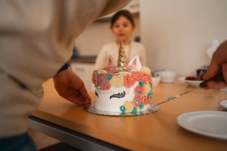 Un gâteau à la licorne décoré de façon fantaisiste avec une corne d'or et des fleurs de glaçage colorées occupe le devant de la scène lors d'une célébration d'anniversaire des enfants, promettant une expérience de dessert magique. Haute qualité 4k