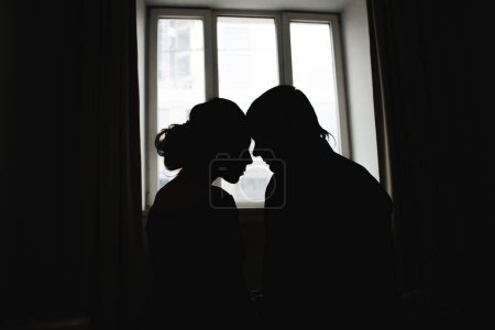 Téléchargez les photos : Silhouettes romantiques d'un couple amoureux contre la fenêtre - en image libre de droit
