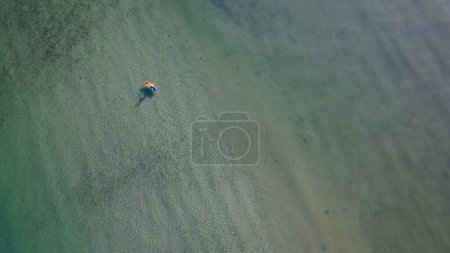 Téléchargez les photos : Vue aérienne d'une personne sur un bateau à aubes à Ballynamona plage dans le comté de Cork, Irlande, par une journée d'été calme - en image libre de droit