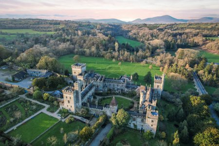 Luftaufnahme des majestätischen Lismore Castle in der Grafschaft Waterford, Irland, gebadet im goldenen Schein der untergehenden Sonne am ersten Frühlingstag, präsentiert seine zeitlose Schönheit und historischen Charme