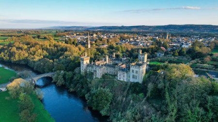 Aerial view of majestic Lismore Castle in County Waterford, Ireland, bathed in the golden glow of the setting sun on the first day of spring, showcasing its timeless beauty and historic charm