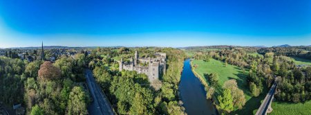 An aerial panorama reveals the majestic Lismore Castle in County Waterford, Ireland, set against a flawless spring sky