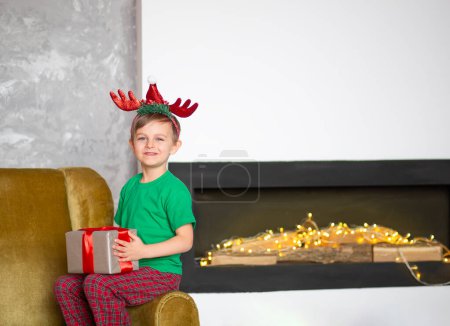 Foto de Feliz niño en pijama con un regalo envuelto en la mañana de Navidad. Un tiempo de milagros y realización de deseos. Feliz Navidad.. - Imagen libre de derechos