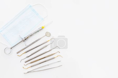 Téléchargez les photos : Concept d'examen dentaire. Porte-dents, outils de dentiste, brosse à dents et masque facial sur fond blanc, pose plate. Place pour le texte. - en image libre de droit