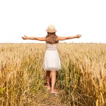 Cute little girl in a hat in a wheat field on a sunny day with her arms wide open above the wheat field. Fresh air, concepts of freedom, joy, childhood, isolate