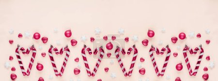 Foto de Arreglo temático navideño con bastones de caramelo, bolas rosas y decoraciones estrella sobre un fondo rosa pastel - Imagen libre de derechos