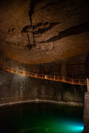 WIELICZKA, POLONIA - 30 DE JUNIO: Escalera subterránea y lago de la cueva de sal Wieliczka. Vista interior de Wieliczka y bochnia minas de sal real texturizado paredes de sal y techo, débilmente iluminado por luces artificiales