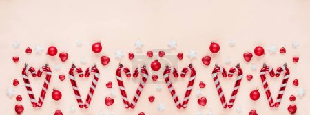 Foto de Arreglo temático navideño con bastones de caramelo, bolas rosas y decoraciones estrella sobre un fondo rosa pastel - Imagen libre de derechos