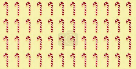 Foto de Arreglo temático navideño con bastones de caramelo, bolas rosas y decoraciones estrella sobre un fondo amarillo pastel - Imagen libre de derechos