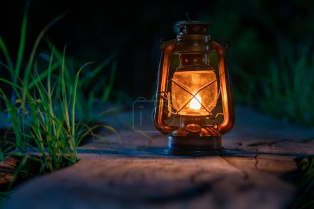 Téléchargez les photos : Lampe à huile antique sur le vieux plancher de bois dans la forêt la nuit atmosphère de camping - en image libre de droit