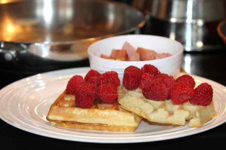 Foto de White plate with waffles, raspberries and bowl with diced sausage - Imagen libre de derechos