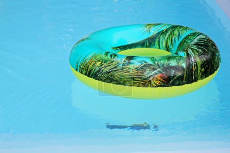 Foto de Estampado de hojas verdes en un neumático de vinilo flotando en una piscina - Imagen libre de derechos