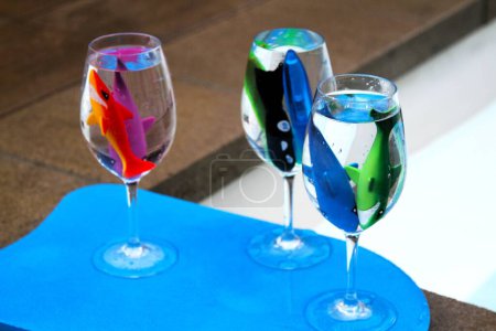Foto de Pescado de goma en copas de vino de plástico en una bandeja azul junto a una piscina - Imagen libre de derechos