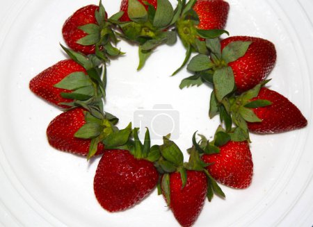 Circle of strawberries with hulls on a white background