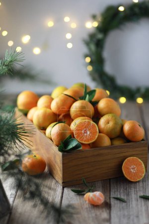 Photo for Christmas or New Years rustic still life of tangerines in a wooden rectangular box and spruce branches on wooden background. - Royalty Free Image