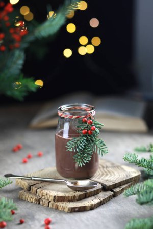 Photo for Hot chocolate in glass jar decorated with fir and red berries on festive background. - Royalty Free Image