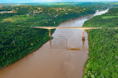 Photo for Aerial view of The Tancredo Neves Bridge, better known as Fraternity Bridge connecting Brazil and Argentina through the border over the Iguassu River, with the Argentinian city of Puerto Iguazu in the back. - Royalty Free Image