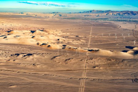 Foto de Vista aérea del desierto de Atacama con la ciudad de Calama al fondo y una carretera y turbinas eólicas en primer plano - Imagen libre de derechos