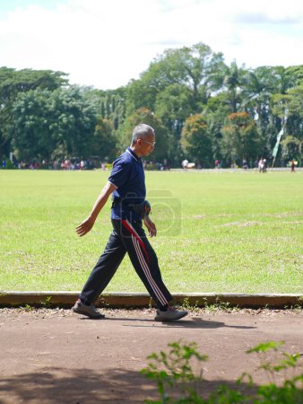 Téléchargez les photos : Malang, indonésie - 23 février 2023 : un vieux piéton fait de l'exercice autour du terrain à pied - en image libre de droit