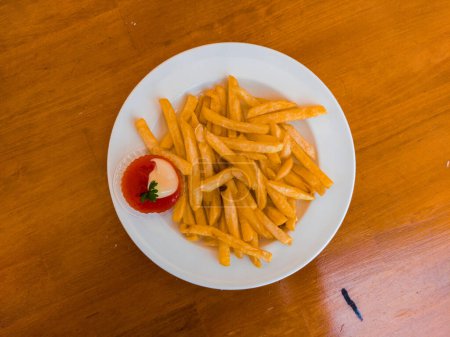 Téléchargez les photos : Close up photo du haut d'une assiette de frites avec ketchup ou sauce tomate sur une table en bois photographiée d'en haut - en image libre de droit
