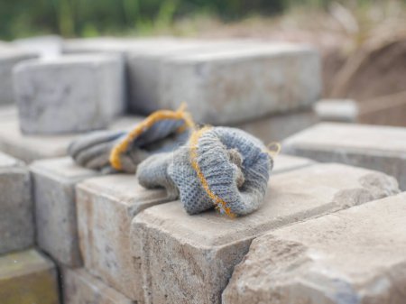 Téléchargez les photos : Une paire de gants de laine qui ont été utilisés pour soulever des blocs de pavage afin qu'ils ne soient pas glissants et blessent les mains des travailleurs - en image libre de droit