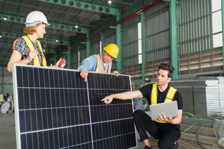 Téléchargez les photos : Équipe d'ingénieurs et de techniciens travaillant ensemble sur un panneau solaire dans une usine. - en image libre de droit