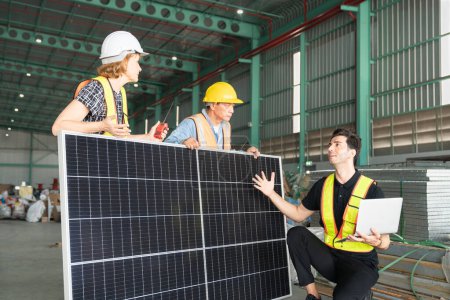 Téléchargez les photos : Équipe d'ingénieurs et de travailleurs utilisant des panneaux solaires dans un grand entrepôt.Il s'agit d'un entrepôt de transport et de distribution de marchandises. - en image libre de droit