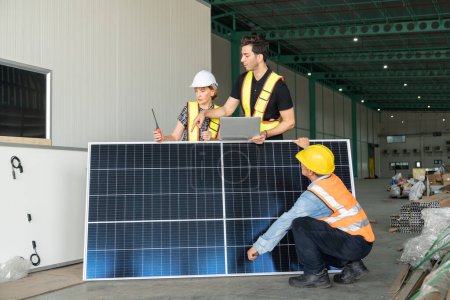 Téléchargez les photos : Equipe d'ingénieurs et techniciens travaillant sur des panneaux solaires dans un entrepôt. - en image libre de droit