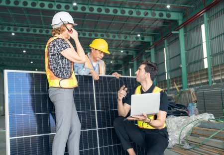 Téléchargez les photos : Ingénieur et technicien travaillant ensemble dans une centrale solaire. Ils utilisent un ordinateur portable et walky-talky avec le sourire. - en image libre de droit