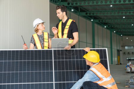 Téléchargez les photos : Équipe d'ingénieurs et de techniciens travaillant ensemble sur des panneaux solaires dans un entrepôt. - en image libre de droit