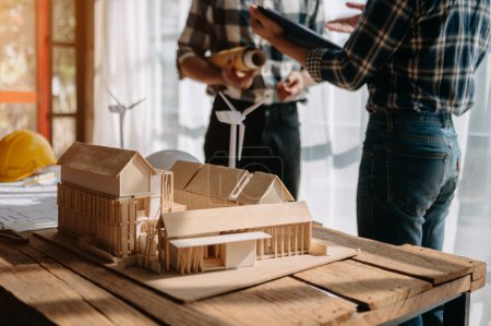 Photo for Close up shot of scale model house on table with architects. Two architects making architectural model in office together. to form a new building - Royalty Free Image