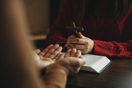 Foto de Imagen recortada del hombre y la mujer orando en la mesa con la cruz y el libro de la Biblia - Imagen libre de derechos
