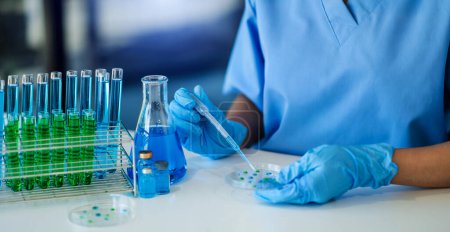 biotecnóloga mujer probando sustancias químicas azules en laboratorio. covid-19 analytics
